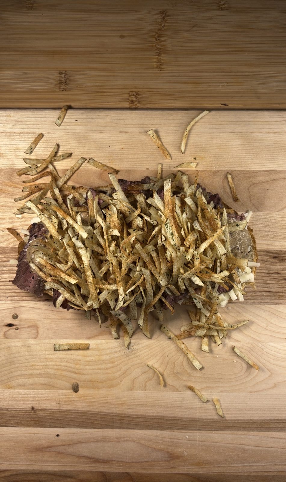 Shoestring fries piled high on top of sliced steak and peppercorn sauce on a slice of sourdough